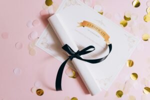 Certificate of achievement on pink surface with confetti and rolled document tied with ribbon.